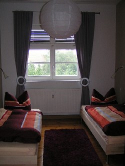 Im kleinen Schlafzimmer steht ein Kleiderschrank und 2 einzelne Betten mit Leselampen